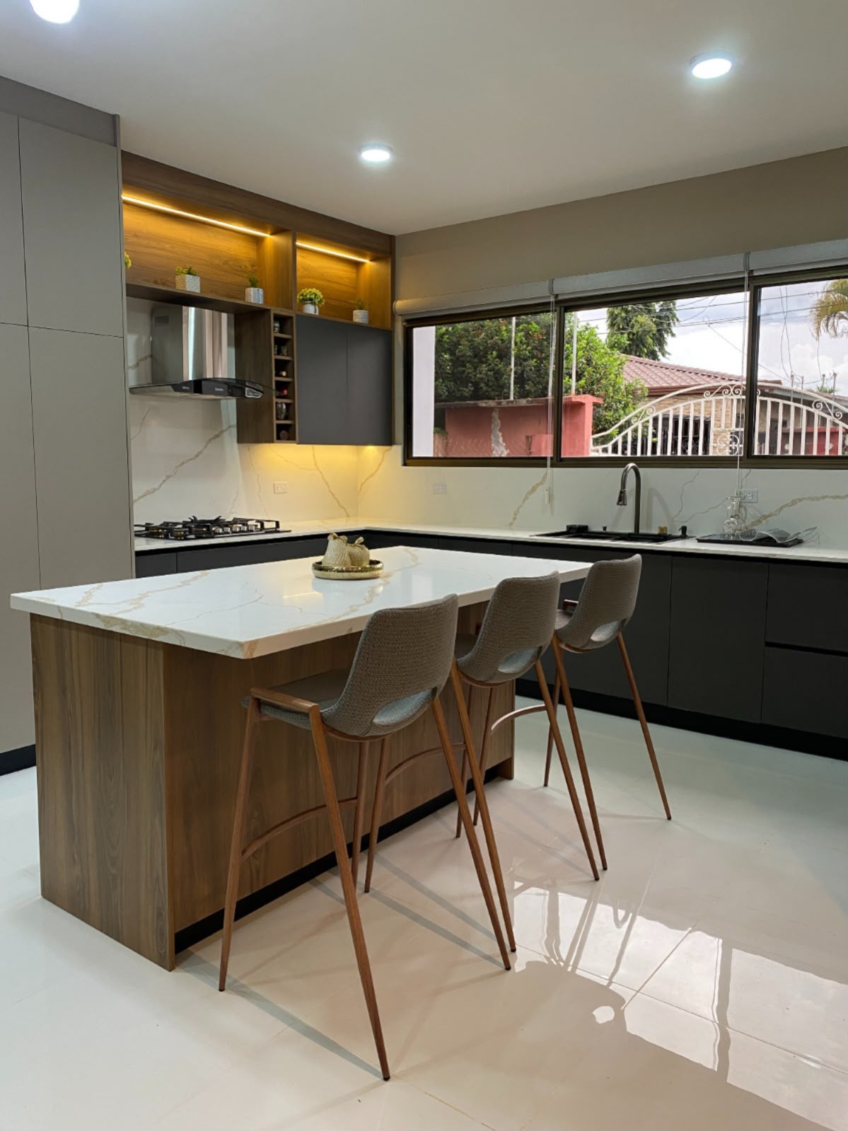 Cocina gris con isla de madera y cuarzo veteado, proyecto RedDesign